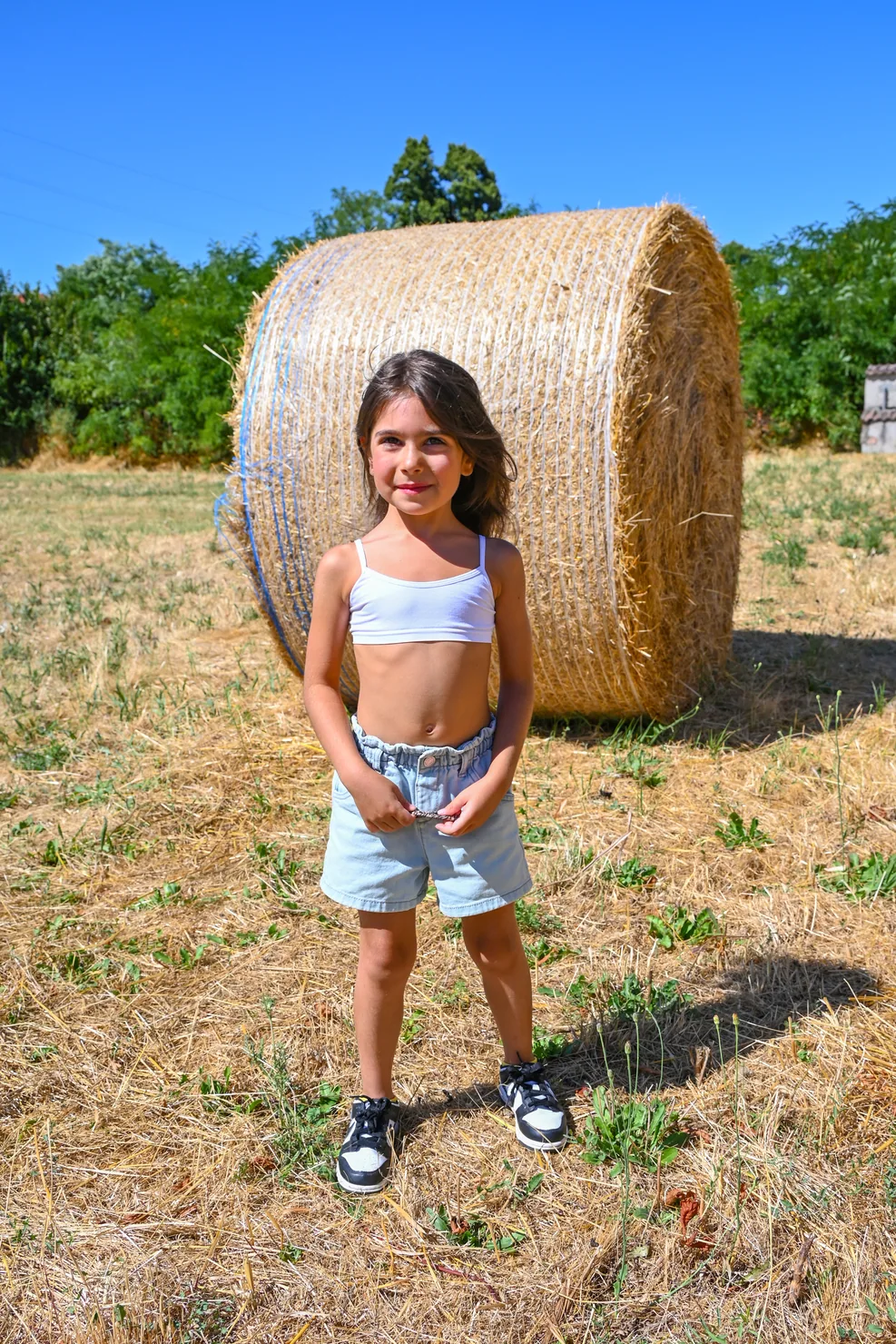 Gaia in piedi accanto alle balle di fieno in campagna
