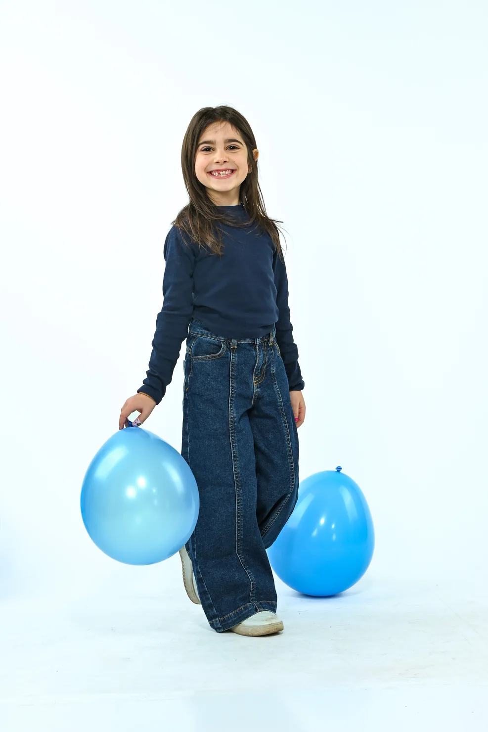 Gaia tiene un palloncino azzurro in uno studio bianco